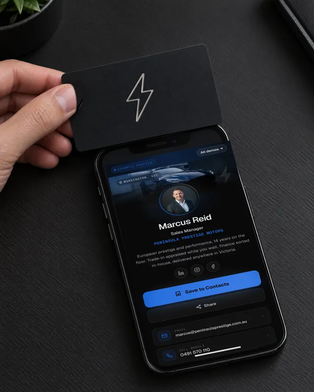 The matte black ZapCard held to a phone that shows Marcus Reid's example ZapCard profile